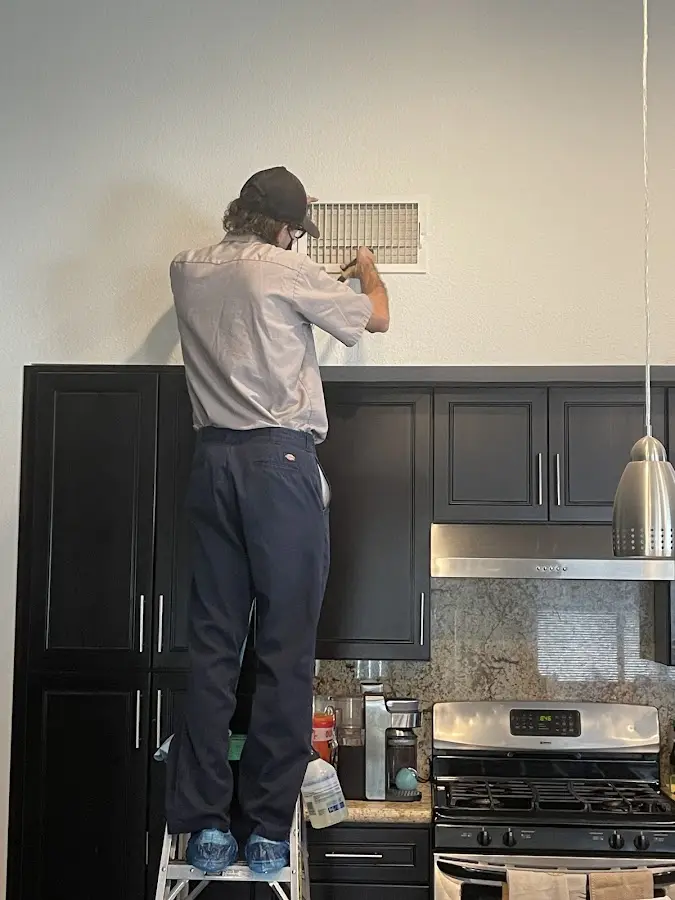 Technician inspecting an air vent during HVAC service in Elmwood